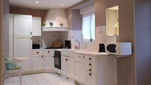 A modern kitchen with white cabinets, a stove, a microwave, and a sink.