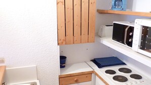 A compact kitchen with a sink, stove, microwave, and wooden cabinets. - 3-room duplex sleeps 6 near slopes in Arc 1800 (Les Arcs 1800)