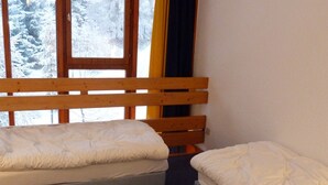 A room with two single beds, wooden headboards, and a window with a view of snow-covered trees. - 3-room duplex sleeps 6 near slopes in Arc 1800 (Les Arcs 1800)
