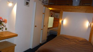 Une chambre confortable avec un lit superposé, des meubles en bois et des lampes fixées au mur.