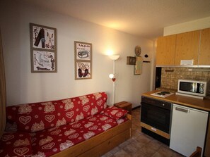 Cozy living space with a kitchenette, sofa, and framed ski-themed artwork.