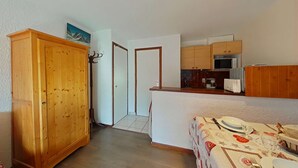 A compact kitchen with wooden cabinets, a microwave, and a dining area with a table set for two. - Comfortable studio with parking in Grand Bornand (Le Grand-Bornand)