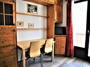 Cozy room with a dining table, TV, and a window with a curtain.