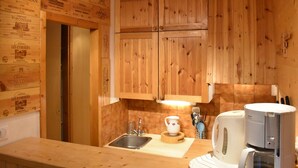 Eine Küche mit Holzausstattung, einem Spülbecken, einer Kaffeemaschine und einem Wasserkocher.