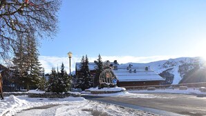Schneebedeckte Landschaft mit einem Gebäude im traditionellen Chalet-Stil, umgeben von schneebedeckten Bäumen und einem klaren Himmel.