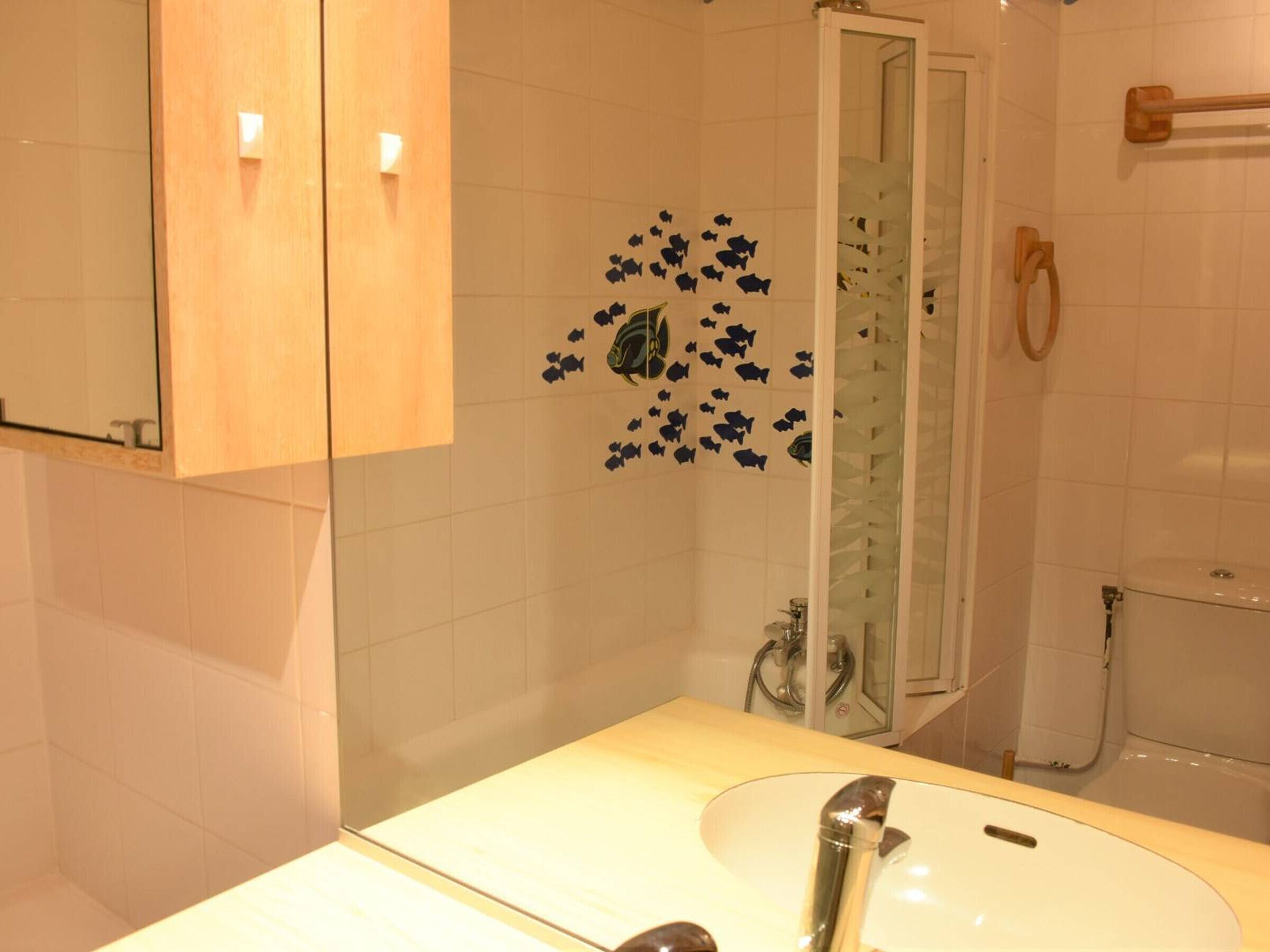 A bathroom with a white sink, a mirror, and a shower area.