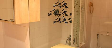 A bathroom with a white sink, a mirror, and a shower area.