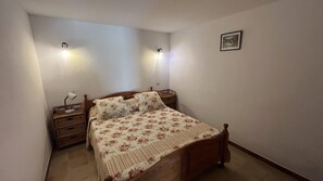 Ein Schlafzimmer mit einem hölzernen Bett, zwei Nachttischen, einer Wandlampe und einem gerahmten Bild.