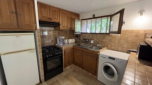 Une cuisine compacte équipée d’un réfrigérateur, d’une cuisinière, d’un four, d’un évier et d’un lave-linge.