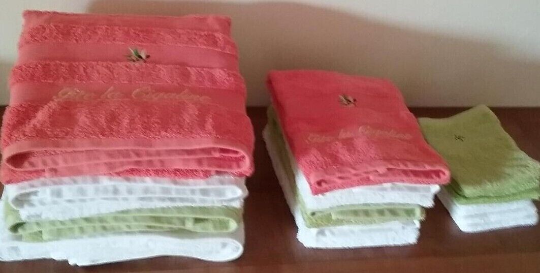 Ein Stapel gefalteter Handtücher in Rosa, Weiß und Grün auf einer Holzoberfläche.
