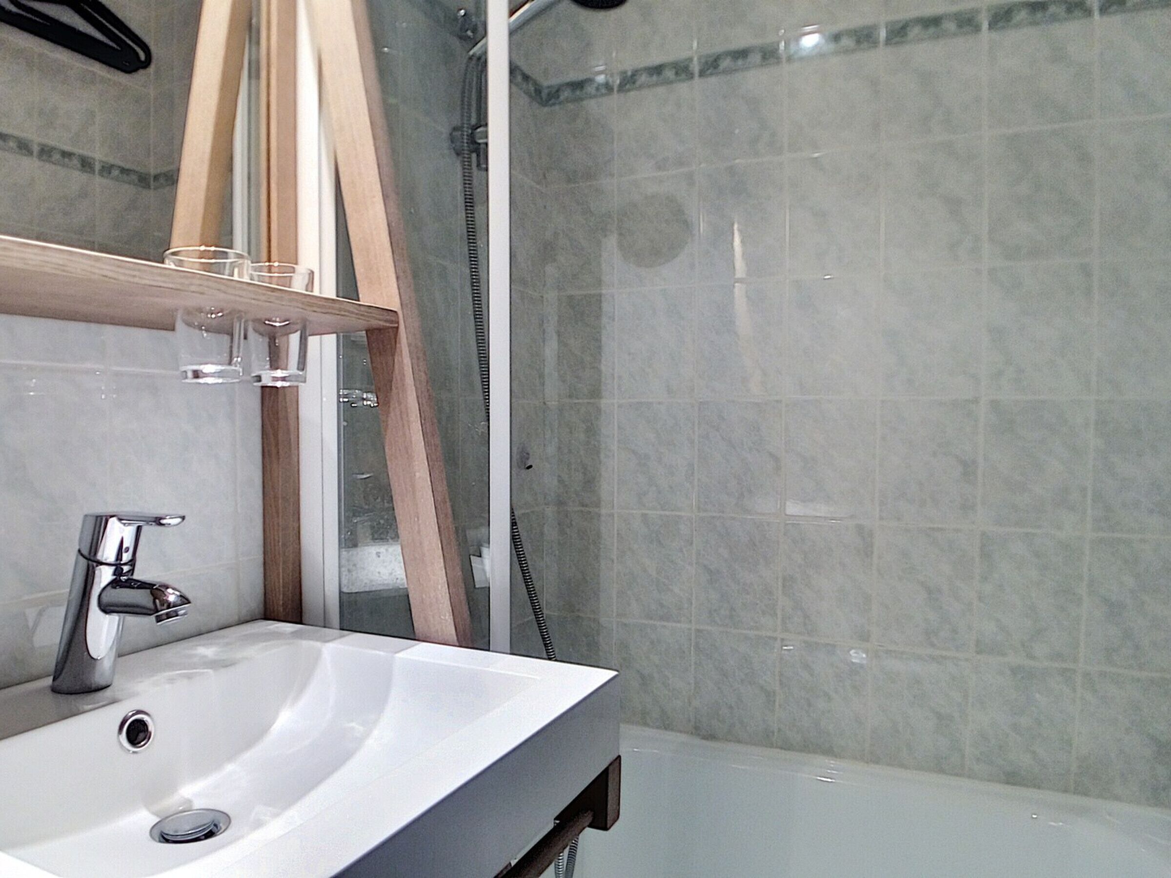 A bathroom with a white sink, a mirror, and a shower area.