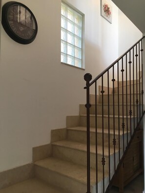 A staircase with a black metal railing and beige steps.