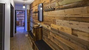 A hallway with wooden paneling, a bench, a mirror, and a hanging light fixture. - Spacious 3-Bedroom Apartment for 8   – Near Ski Slopes in Gourette, Fully Equipped (Gourette)