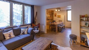 A cozy living room with a sofa, coffee table, and a dining area with a table and chairs. - Spacious 3-Bedroom Apartment for 8 – Near Ski Slopes in Gourette, Fully Equipped (Gourette)
