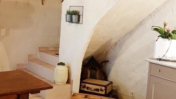 A rustic interior with a wooden staircase, a dining table, and a cabinet. - Camfier self-catering cottage (TOURVES)