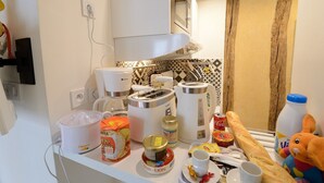 A kitchen with a microwave, coffee maker, toaster, and various food items on the counter. - D4DD Family white (Paris)