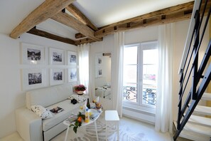 A bright room with a wooden ceiling, white walls, and a balcony with a wrought iron railing. - D4DD Family white (Paris)
