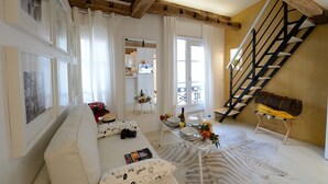 A living room with a white sofa, a dining table set with plates and a vase of flowers, a staircase with a black railing, and a zebra print rug. - D4DD Family white (Paris)
