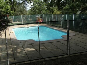 A rectangular swimming pool with a clear blue water, surrounded by a metal fence and a paved deck. - Villa la Jean Martiale (BAGNOLS EN FORET)