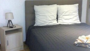 Une chambre à coucher avec un lit, deux oreillers, une table de chevet avec une lampe et deux tableaux encadrés accrochés au mur.