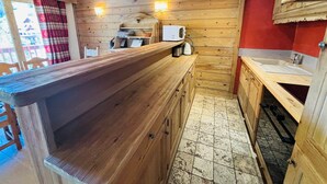 Een kleine keuken met houten kastjes, een aanrecht, een spoelbak en een magnetron.