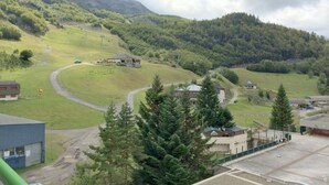 A rural landscape with a winding road, a small building, and a forested hill.