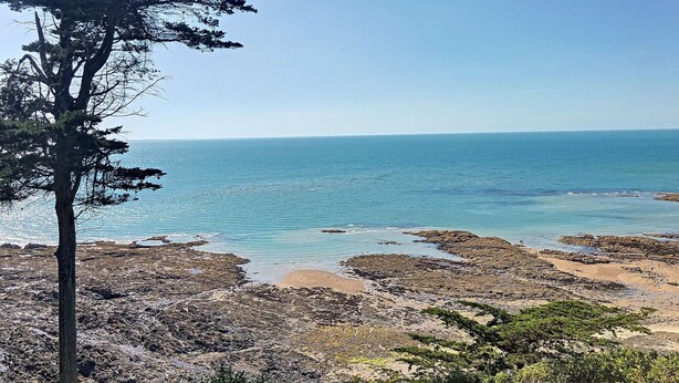 A coastal landscape with rocky terrain and a clear view of the sea.