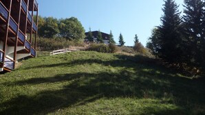 A multi-story building with balconies, a grassy area, and a distant house.