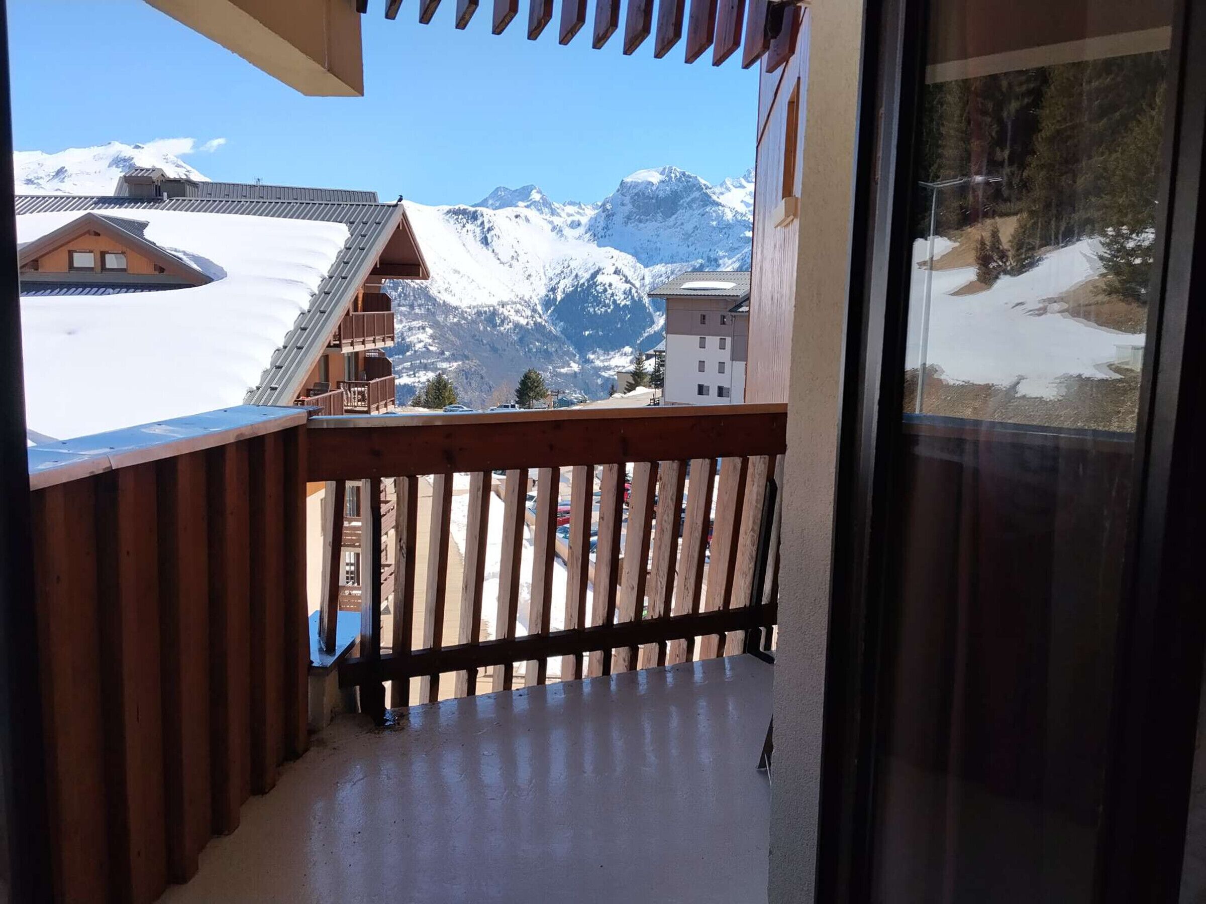 A balcony with a wooden railing overlooking a snowy mountain landscape.