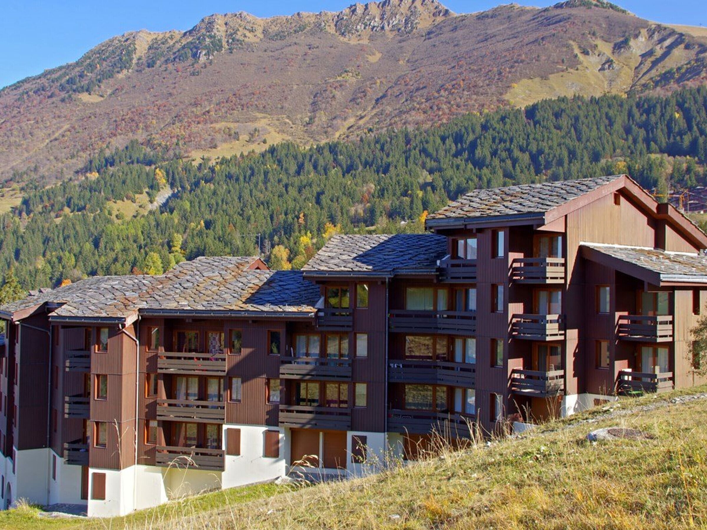 Ein modernes, mehrgeschossiges Gebäude mit Balkonen vor einer Bergkulisse.