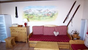 Una sala de estar acogedora con un sofá y una mesa de madera, y un cuadro de un paisaje montañoso en la pared.