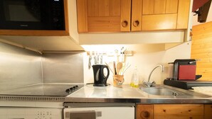 Een keuken met roestvrijstalen apparatuur, houten kastjes en een magnetron.