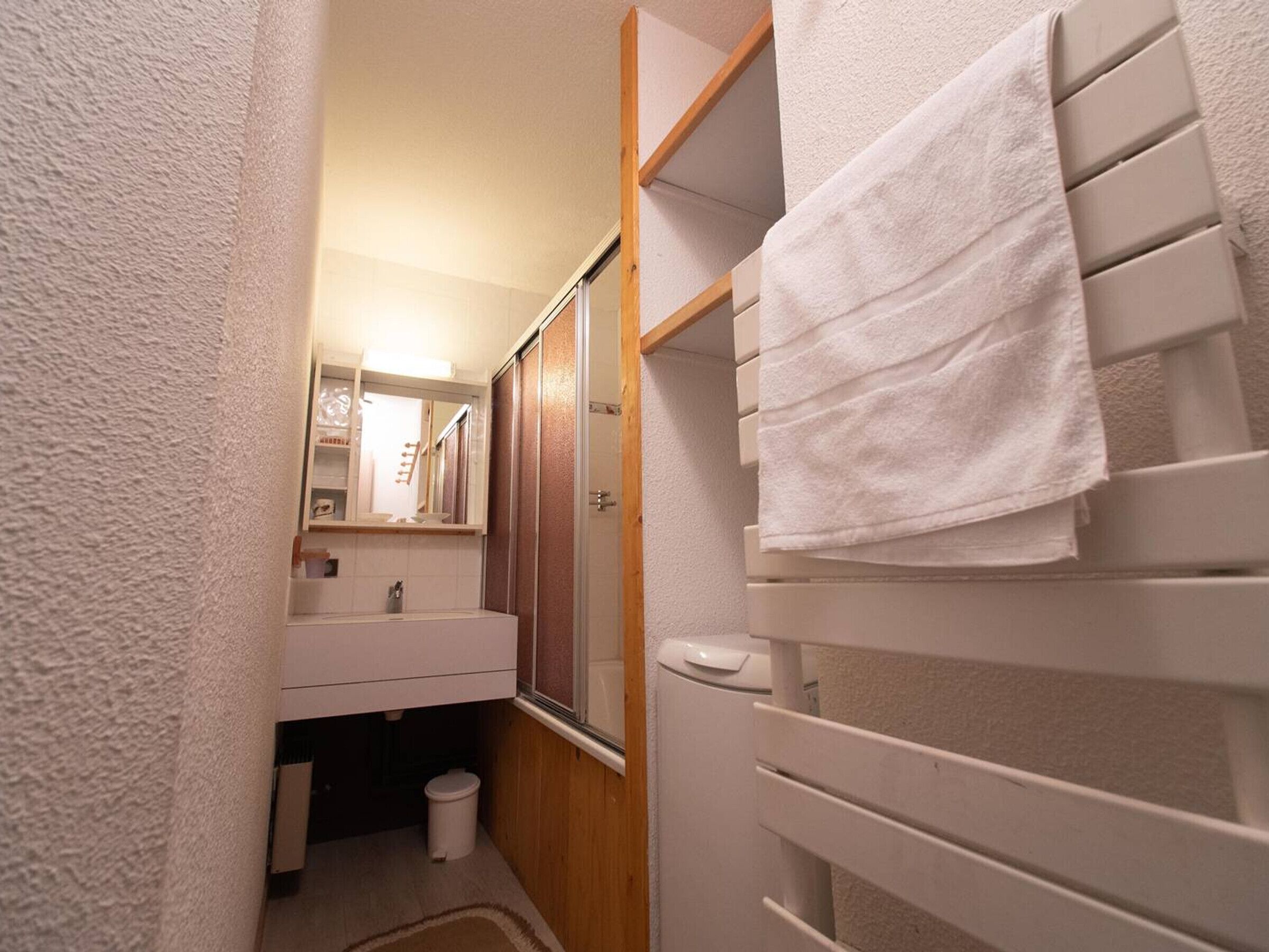 A compact bathroom with a white sink, mirror, and towel rack.