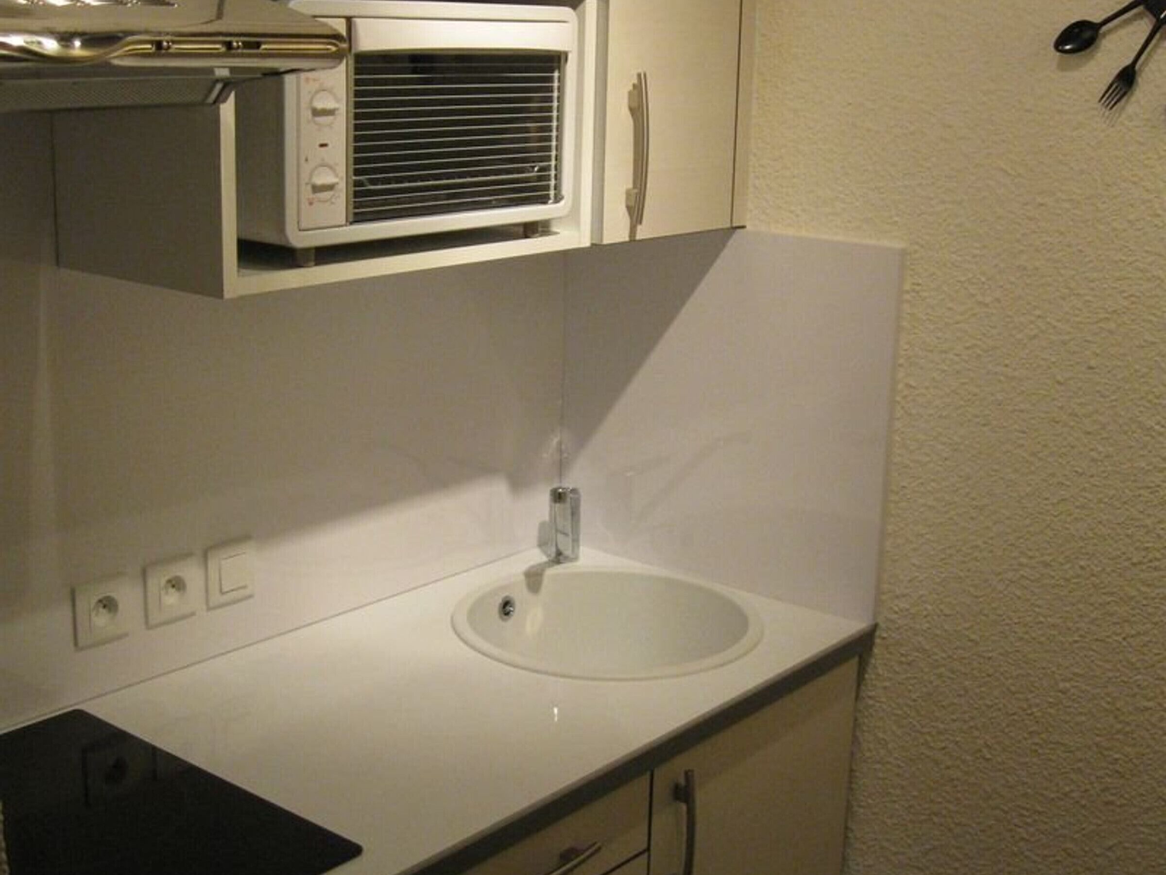 A compact kitchen with a microwave, sink, and cabinets.