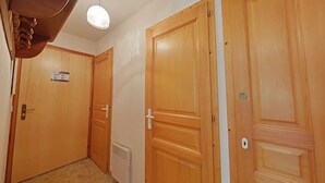 Ein Korridor mit Holztüren, einer weißen Deckenleuchte und einer weißen Wand mit einem Schild.
