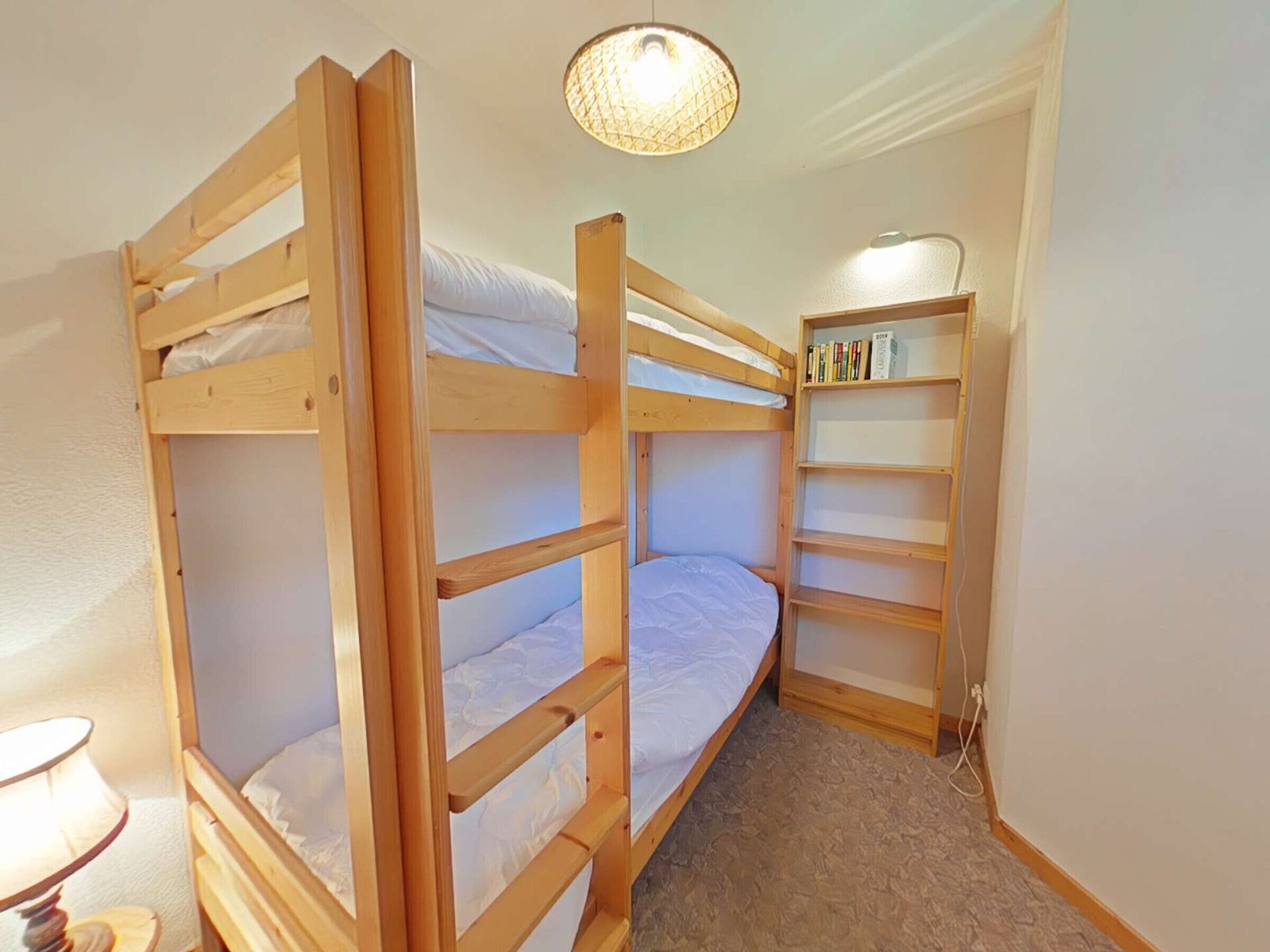 A bunk bed room with a small desk and bookshelf.