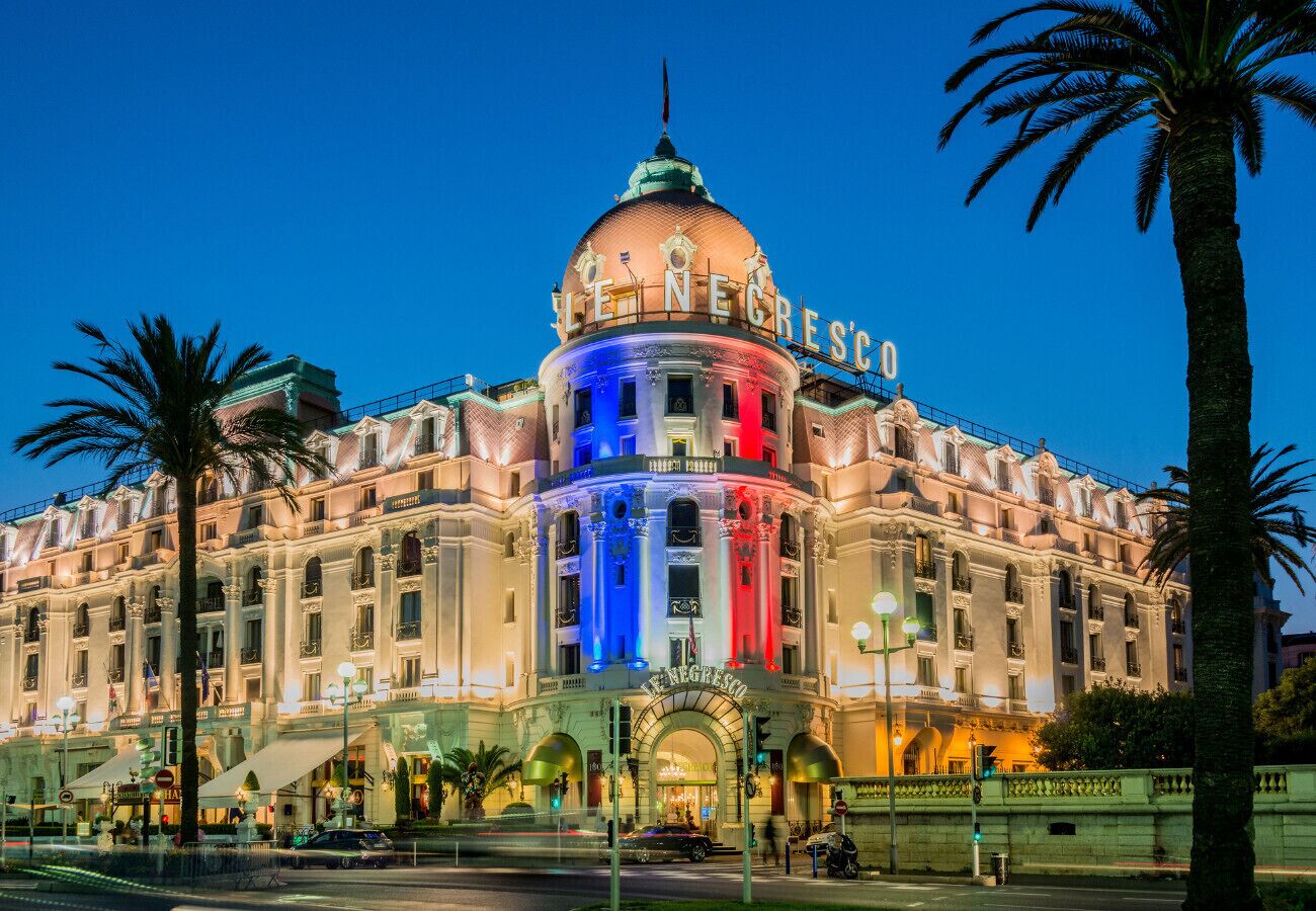 Un gran edificio histórico con una cúpula destacada y el nombre "LE NEGRESCO" iluminado en la fachada.