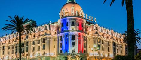 Un gran edificio histórico con una cúpula destacada y el nombre "LE NEGRESCO" iluminado en la fachada.