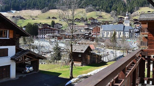 A view of a town with traditional wooden buildings, a church, and a mountain backdrop. - Cozy 2-Room Apartment with Mountain Views, Near Village Center and Ski Trails - Sleeps 4 (Le Grand-Bornand)