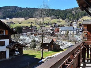 Blick auf eine Stadt mit traditionellen Holzbauten, einer Kirche und einem Berg im Hintergrund.