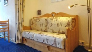 A corner room with a wooden bench, a sofa with a patterned cover, a wall-mounted picture, and a floor lamp. - Ski-in studio, 4 pax, pets allowed - Les Arcs 1800 (Les Arcs 1800)