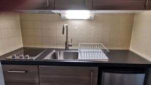 A kitchen with a stainless steel sink, a dish rack, and a built-in oven. - Cozy 5-person studio near slopes, parking included (La Mongie)