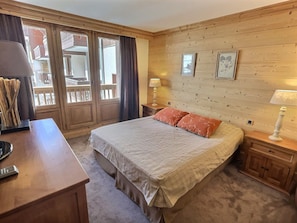 A bedroom with a bed, bedside tables, a desk, and a window with curtains.