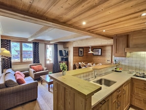 A spacious living area with a sofa, a dining table, and a kitchen with wooden cabinets and a large island.