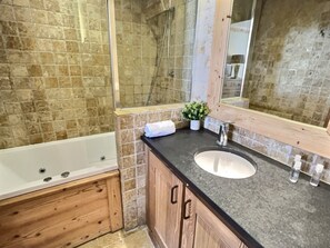 A bathroom with a bathtub, a sink, a mirror, and a shower area.