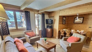 Een gezellige woonkamer met een bank, fauteuils, een salontafel en een televisie.