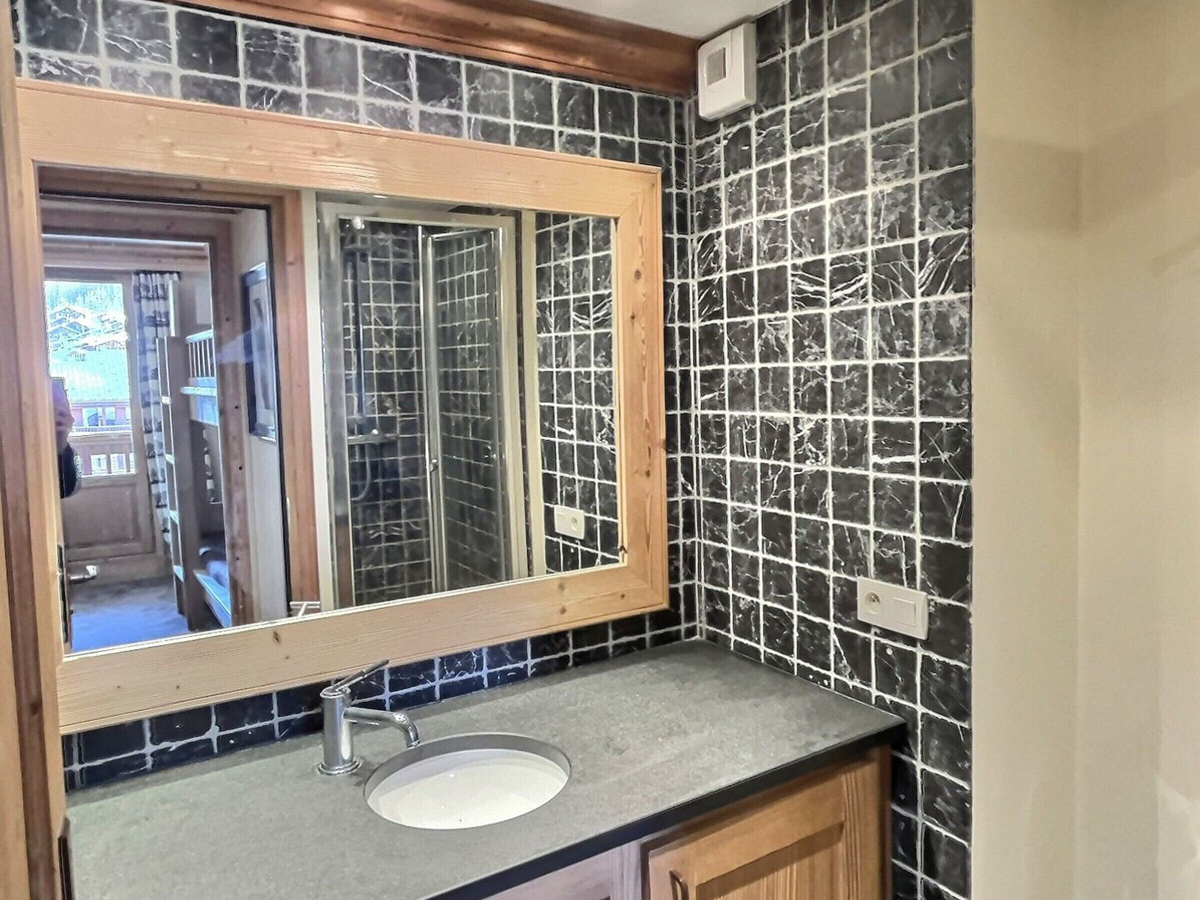 A bathroom with a large mirror, a sink, and a tiled backsplash.