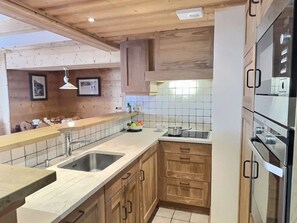 A kitchen with wooden cabinets, a double sink, a stove, and a tiled backsplash.