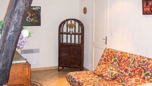 Ein Zimmer mit einem Holzkasten, einem Sofa mit buntem Muster und einer Tür mit weißem Rahmen.