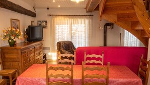Ein Essbereich mit Tisch, Stühlen, einer Couch, einem Fernseher und einer dekorativen Vase.